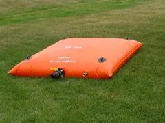 Orange rectangular pillow tank designed for water storage placed on grass.