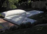 Large white bladder tanks installed in a residential backyard for under-deck water storage.