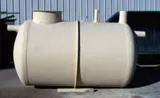 A beige fiberglass underground storage tank with multiple connection points, suitable for water or wastewater storage.