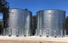 Two corrugated steel tanks on a concrete pad