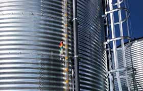 Close up picture of a water level indicator and ladder on the side of a corrugated steel tank