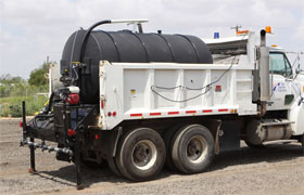 Black water tank mounted on a dump truck, featuring a secure setup for liquid storage and transport.