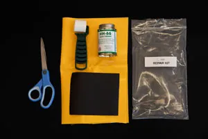 Vinyl repair kit including scissors, adhesive, patch material, and roller for bladder tank maintenance.